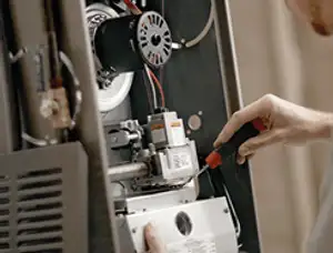 Furnace repair technician inspecting internal components and wiring in Allentown, PA