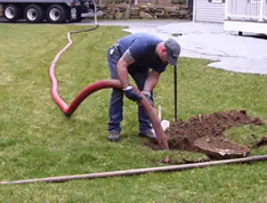 Septic pumping technician servicing a residential septic tank with a vacuum hose in Allentown, PA