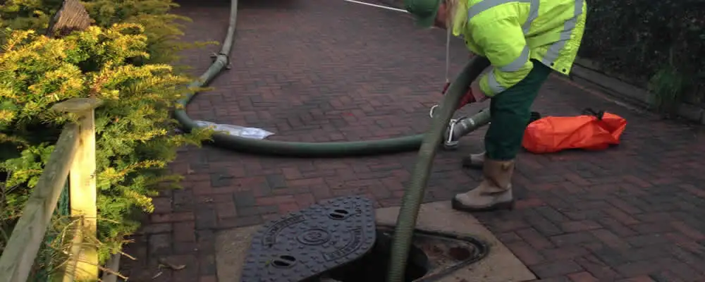Septic tank cleaning technician servicing a septic tank with a vacuum hose in Allentown, PA