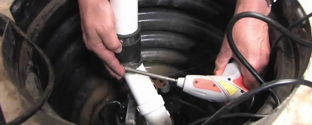 Sump pump installation technician connecting PVC discharge piping in Allentown, PA
